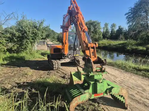 Pelle mécanique équipée d'un grappin de tri en Bretagne Pelle mécanique équipée d'une pince de tri au bord de l'eau en Bretagne - Groupe Beaussire